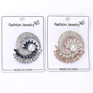 Detailed macro of flower brooches with marquis zircons and pearls on display card