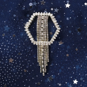 Macro detail of hexagonal tassel brooch with silver rhinestones on blue velvet