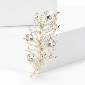Elegant gold feather brooch with white pearls and water drop crystals on a white stand