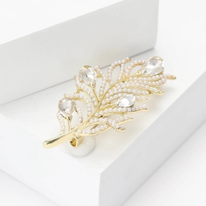 Elegant gold leaf brooch with white pearls and sparkling teardrop rhinestones on white stand