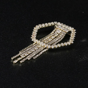 Detailed macro view of a gold-tone geometric brooch featuring shimmering rhinestone tassels