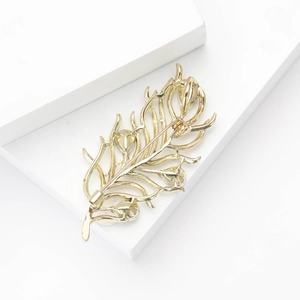 Detailed back view of golden feather brooch showing the safety pin clasp and crystal settings