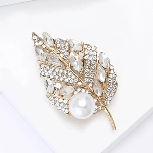 Détail de la broche en forme de feuille avec cristaux, strass et perle blanche