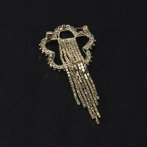 Broche papillon dorée avec franges en strass et épingle de sûreté sur fond sombre