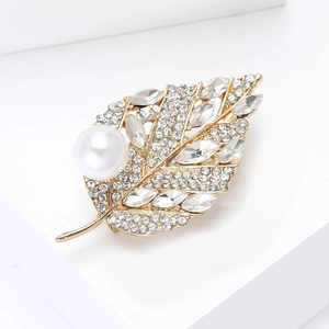 Détail de la broche feuille avec strass brillants et une grande perle sur alliage doré