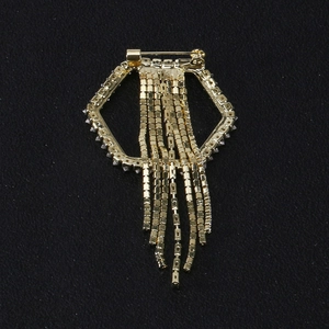 Golden geometric brooch with sparkling crystals and long tassels on black background