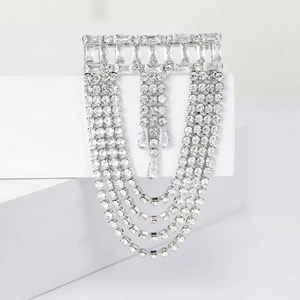 Macro detail of silver tassel brooch with sparkling rhinestones on minimalist pedestal