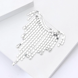 Dettaglio della spilla di lusso con frange di strass e cristalli quadrati su bianco