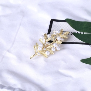 Elegant gold leaf brooch with white pearls for women on silk background cloth