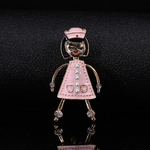Détail d'une broche infirmière avec émail rose, perles nacrées et strass brillants
