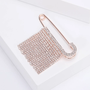 Dettaglio spilla a balia oro rosa con strass e ciondolo a nappa rettangolare elegante