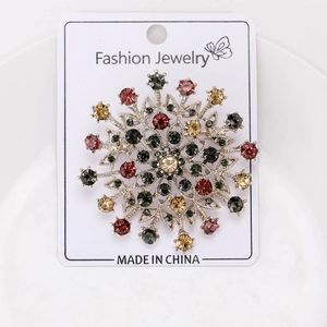 Macro shot of vintage silver snowflake brooch with colorful crystals on a white display card