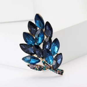 Detailed view of luxury leaf brooch with navy blue crystals and vintage gold finish