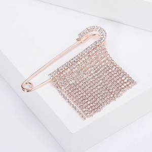 Dettaglio spilla da balia in oro rosa con nappe di strass brillanti e finitura lucida