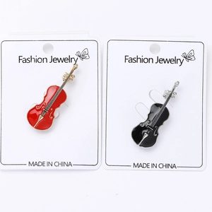 Détail de broches violon en émail rouge et noir avec finition dorée sur carte bijoux