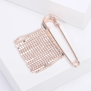 Spilla a balia in oro rosa con nappe di strass brillanti su un supporto bianco minimalista