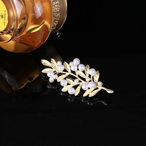 Detailed view of golden leaf brooch with white pearls and frosted vein texture