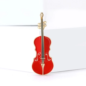 Élégante broche violon en émail rouge avec cordes dorées sur escalier blanc