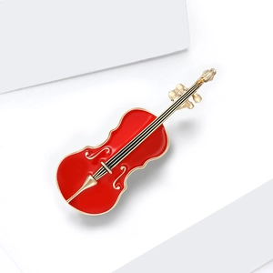 Détail d'une élégante broche violon en émail rouge et cordes dorées sur fond blanc