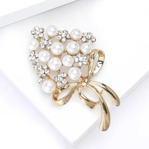 Elegant rhinestone flower bouquet brooch with white pearls and gold bow on white stand