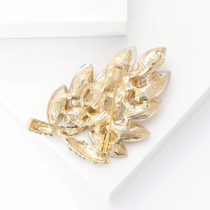 Detail of the high-end golden leaf brooch showing its back clasp and textured metal finish