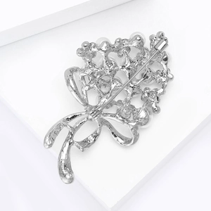 Macro detail of the silver floral brooch back showing the metal mesh and safety pin clasp