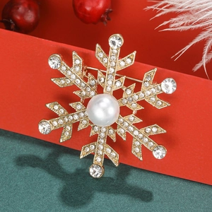 Gros plan d'une broche flocon dorée avec perle et cristaux sur une boîte cadeau rouge
