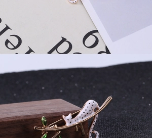 Détail de la broche léopard en émail blanc avec des feuilles vertes sur base dorée
