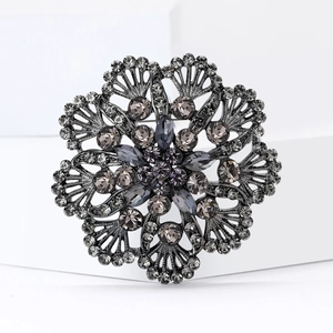 Spilla fiore vintage nero fucile con strass grigi su uno sfondo geometrico bianco