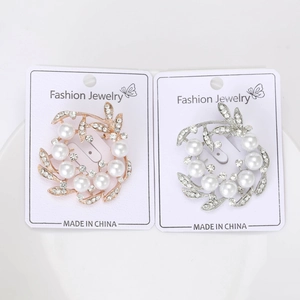 Detail of rose gold and silver floral pearl brooches with leaf pattern and crystals