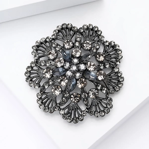 Elegante spilla a fiore vintage in metallo scuro con cristalli grigi su base bianca