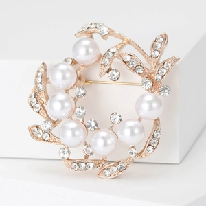 Macro view of a gold flower wreath brooch with white pearls and sparkling zircons