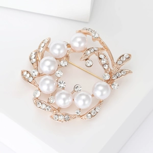 Detailed close-up of a floral rose gold brooch with white pearls and sparkling rhinestones