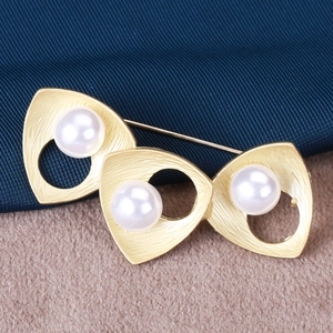 Detailed view of the golden matte brushed brooch with natural white pearls and long pin