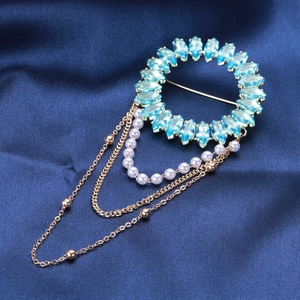 Détail de broche ronde avec cristaux bleu clair et glands multicouches en perles et chaînes dorées