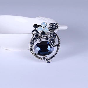 Close-up of vintage tulip brooch with deep blue oval crystal and silver floral details