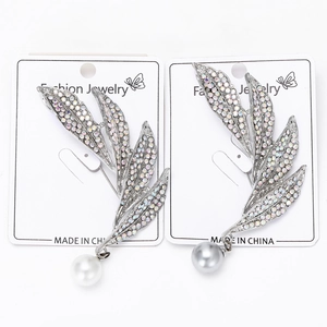 Detailed close-up of leaf brooches with sparkling rhinestones and elegant pearls