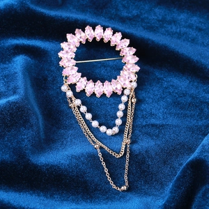 Détail d'une broche dorée de luxe avec cristaux roses et chaînes de perles blanches