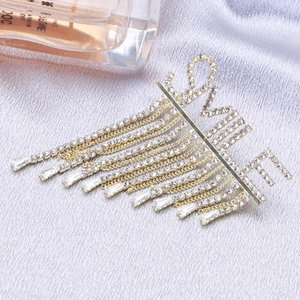 Broche SMILE dorée avec glands en strass scintillants sur un tissu en satin de luxe