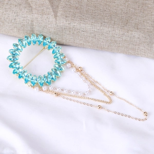 Détail d'une broche ronde de luxe avec cristaux bleu clair et chaînes à pompons dorées