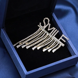 Détail macro de la broche SMILE avec strass étincelants et pampilles élégantes sur velours