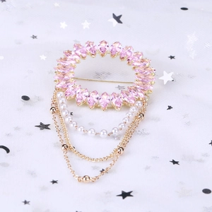 Détail de broche en cristal rose avec perles blanches et pompons à chaîne dorée fine