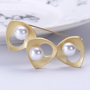 Macro detail of gold brushed brooch featuring three elegant natural freshwater pearls