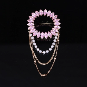 Vue détaillée d'une broche dorée de luxe avec cristaux roses et décoration de gland perlé