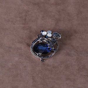Detail view of a vintage floral brooch with dark blue stone and antique silver base