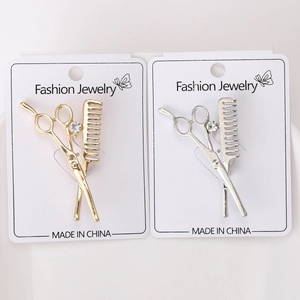 Detailed view of silver and gold scissors and comb brooches with center rhinestone inlay
