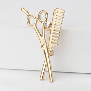 Detailed view of golden scissor and comb brooch with a sparkling rhinestone accent