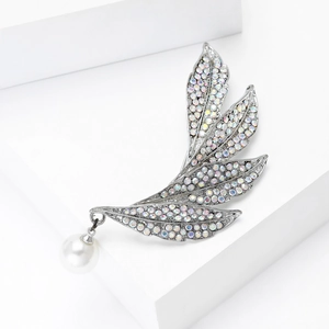 Detailed close-up of a leaf brooch with sparkling colorful crystals and a pearl pendant