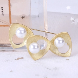Elegant gold triangle brooch with freshwater pearls on a soft fabric star background