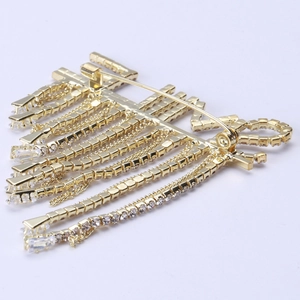 Broche à pompons dorés avec strass blancs montrant la fermeture à épingle à l'arrière
